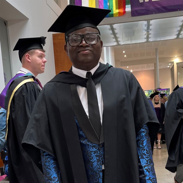 David Ajibola wearing a cap and gown and smiling