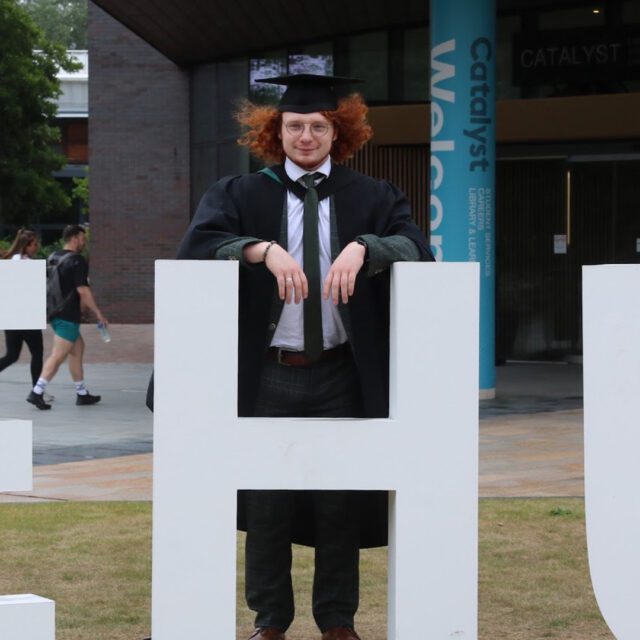 Liam Davies wearing a cap and gown and smiling