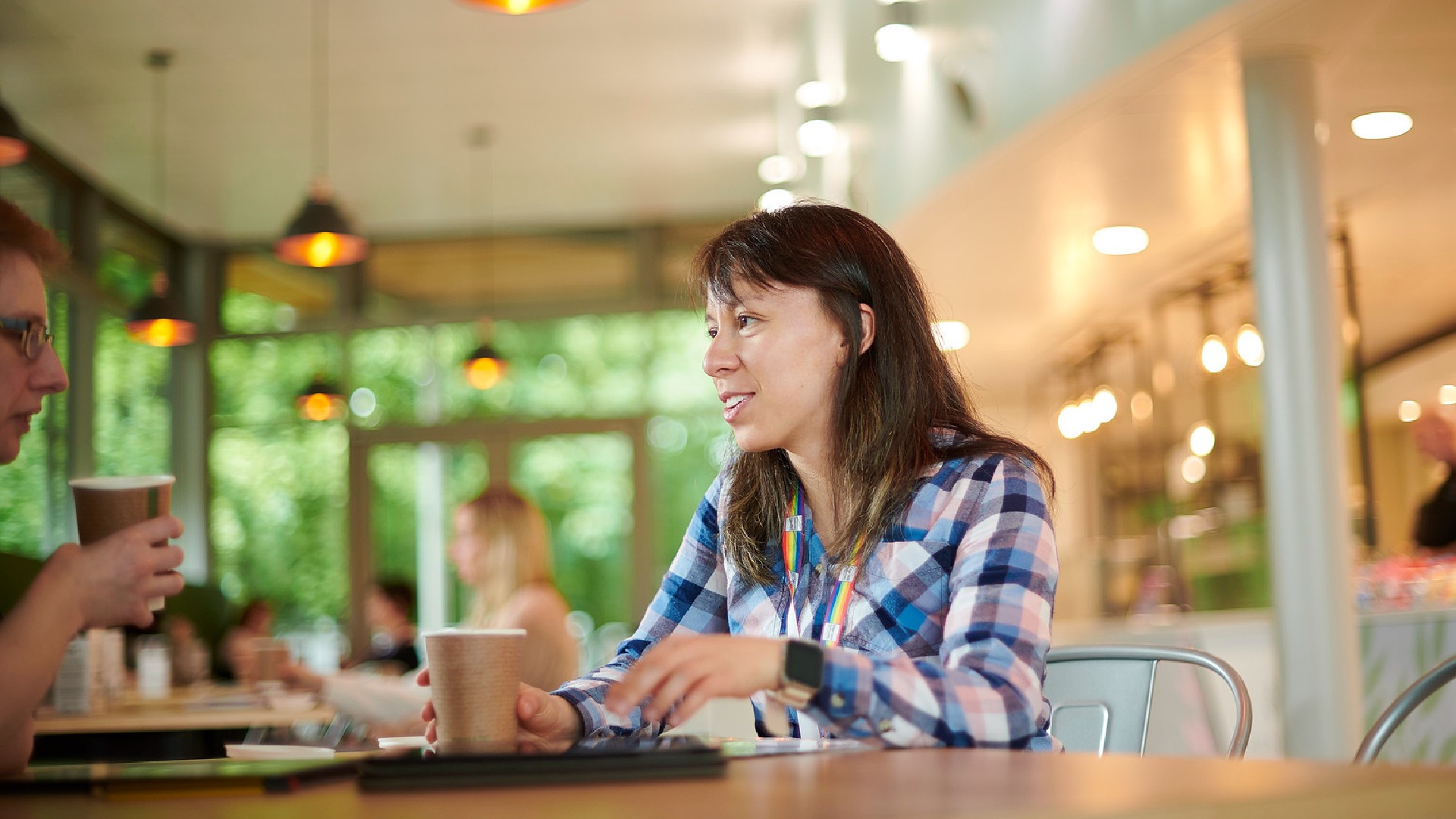 Two students sat in a cafe talking and drinking coffee