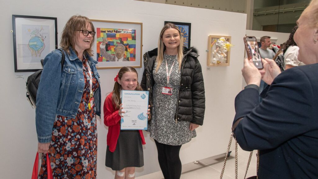 Child at dot-art annual competition holding a certificate
