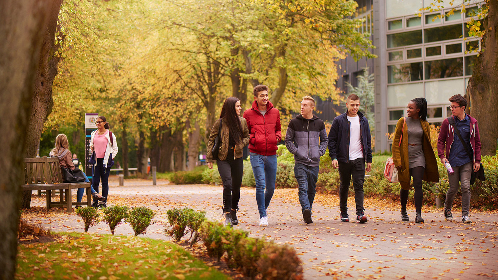 a group of students walk through an autumnal campus setting