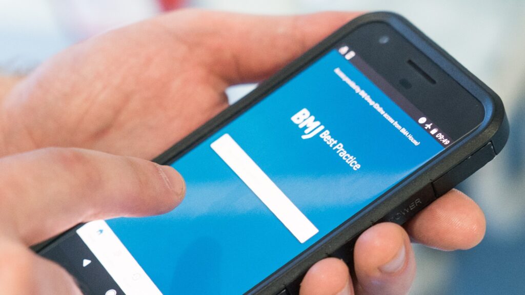A hand holds a mobile phone which displays the BMJ Best Practice app