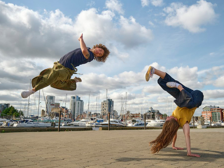 Action shot of two dancers mid-air on the dock.