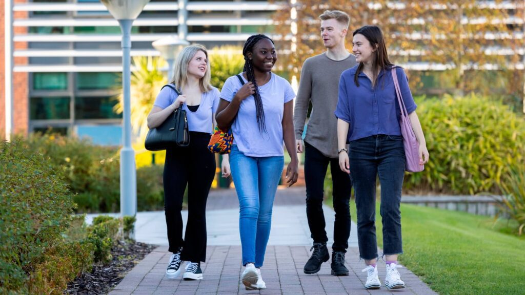 Four students walk near the Faculty of Education.