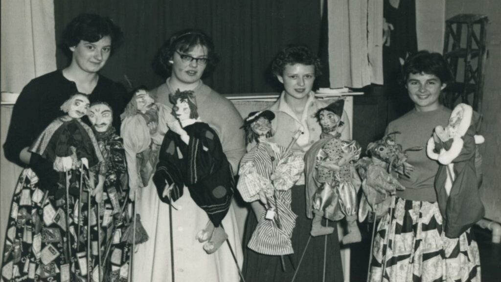 A black and white photo of four people holding hand made puppets.
