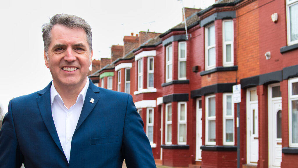 Steve Rotherham standing in a street, with a row of terraced houses in the background