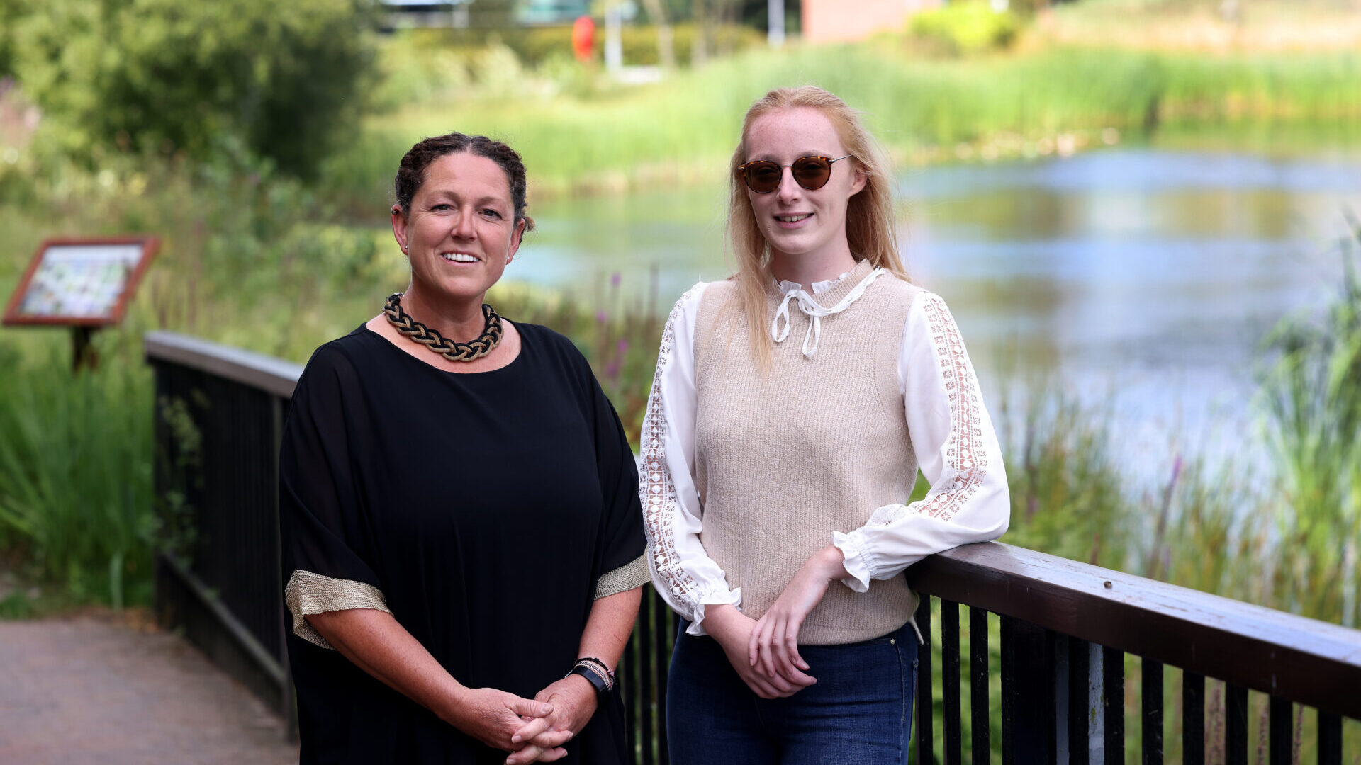 Two women stand next to each other on campus at Edge Hill University