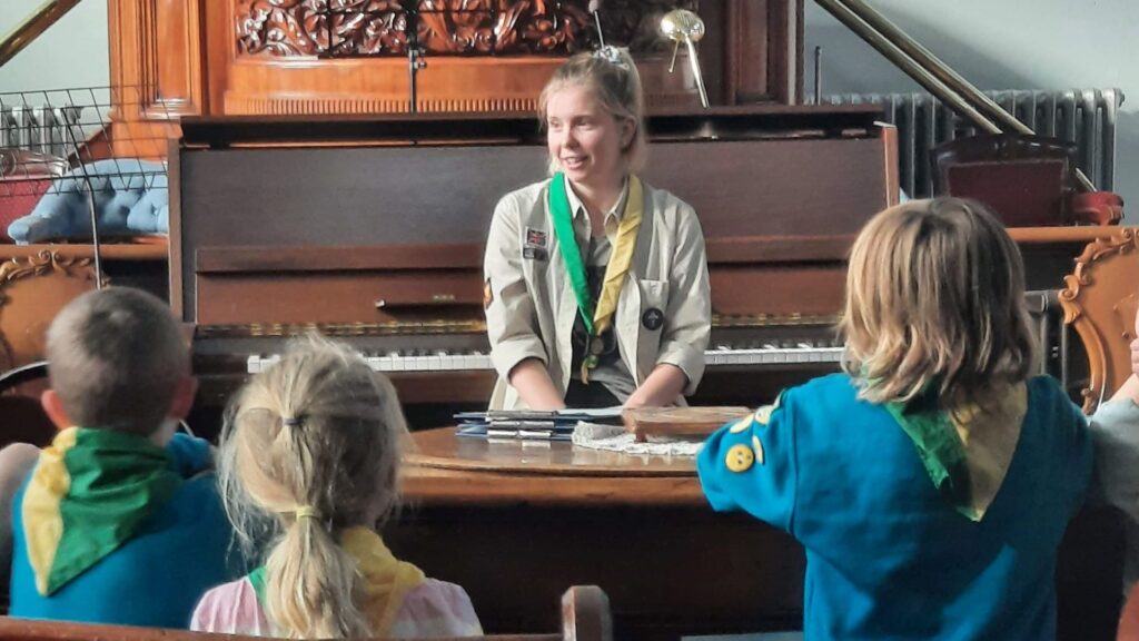 A picture of Emma Hughes in a scout uniform talking to a group of children.
