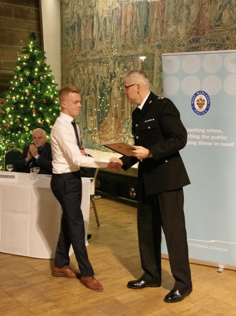 Kien Kirk shakes the hand of a senior police official as he receives an award