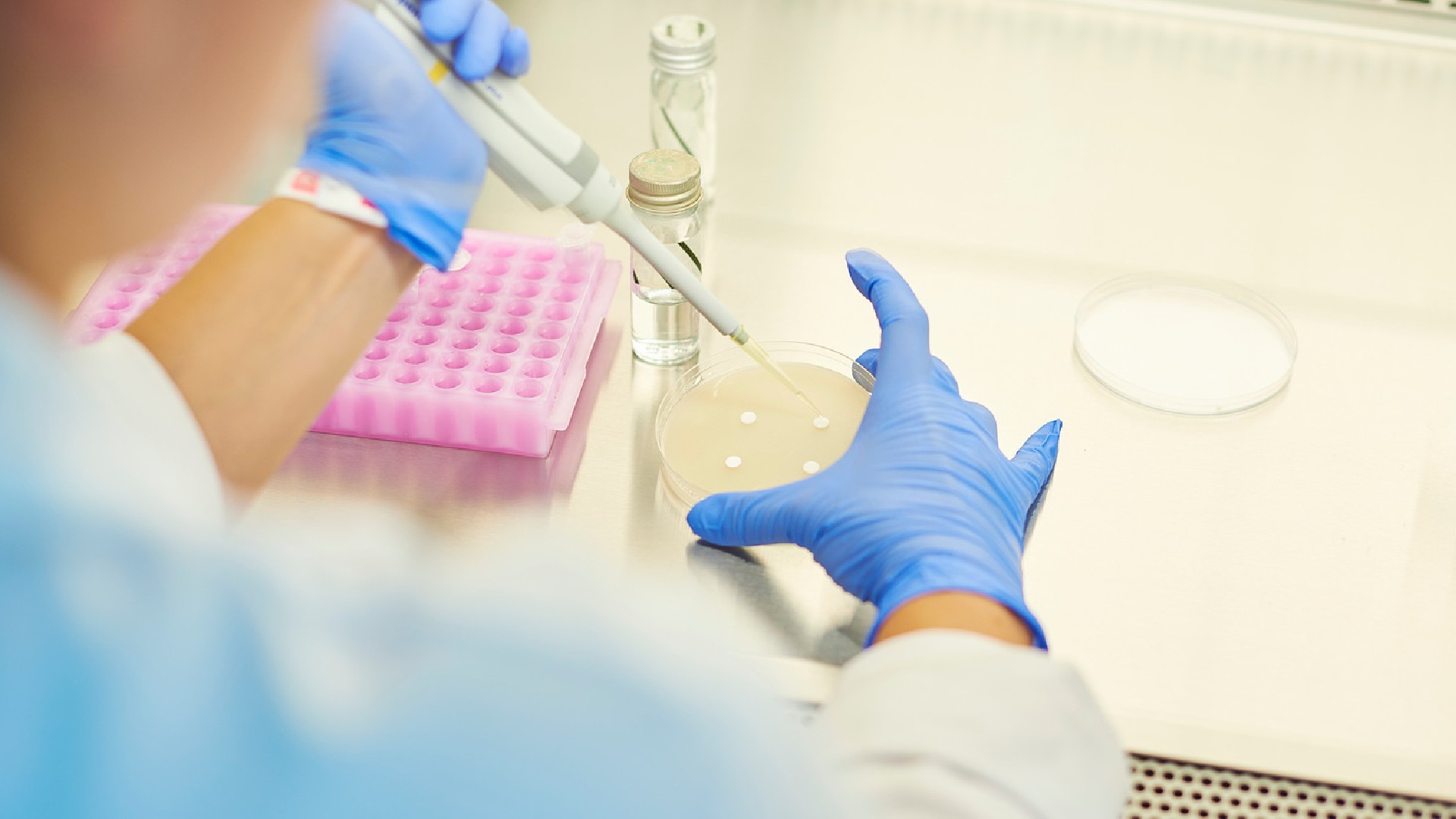 Over the shoulder image of someone using a pipette and lab equipment