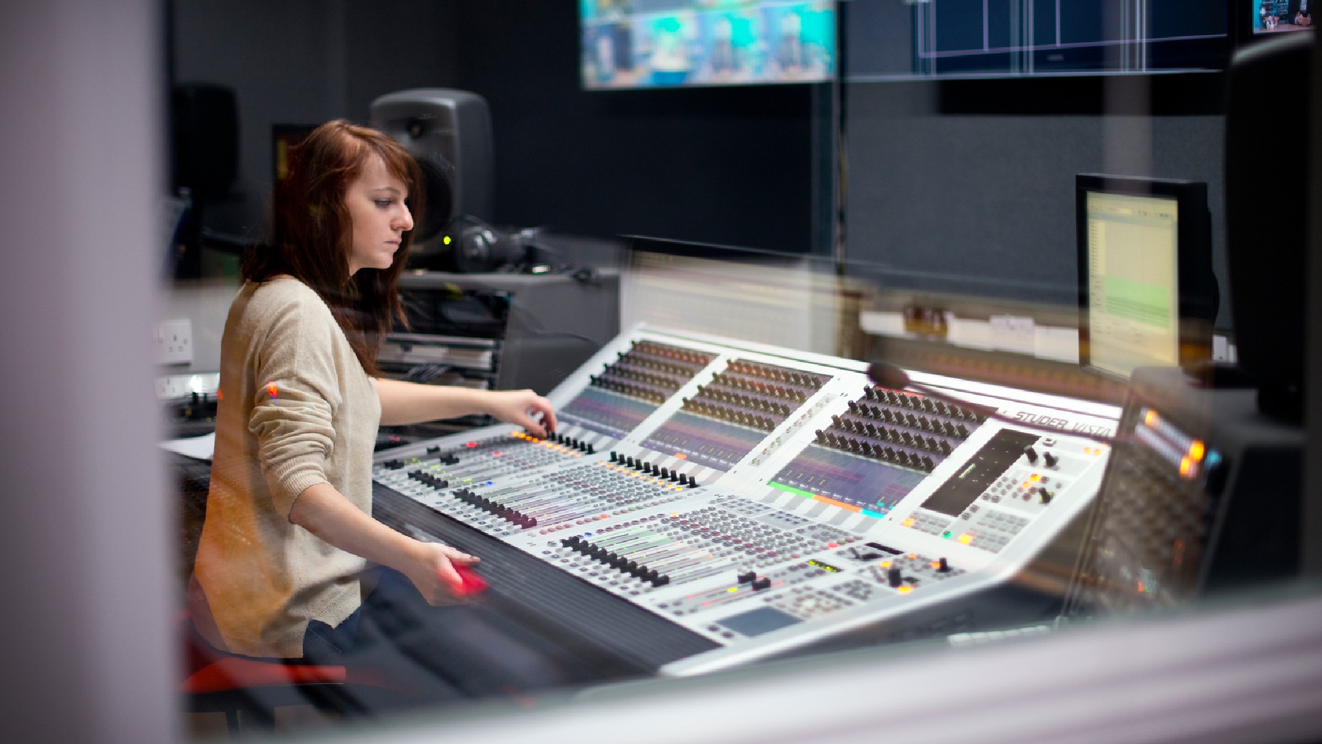 Student using media production equipment including a large mixing desk