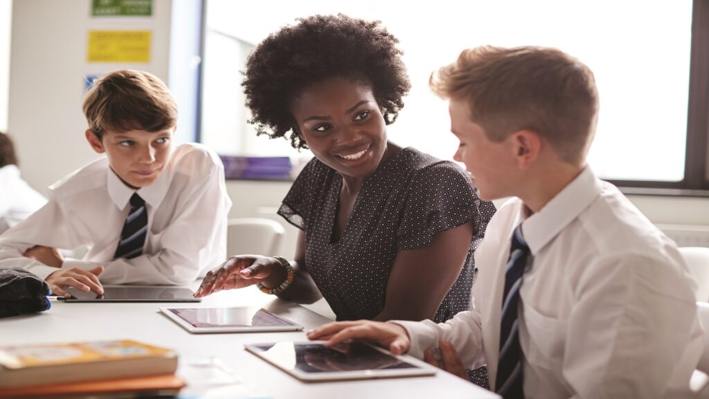 Teacher in classroom with 2 students and ipads on the desk