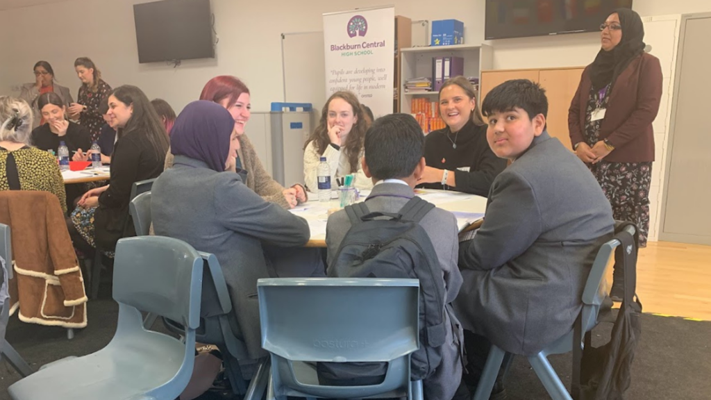 Students of Blackburn Central High School sit around the table of an EAL event
