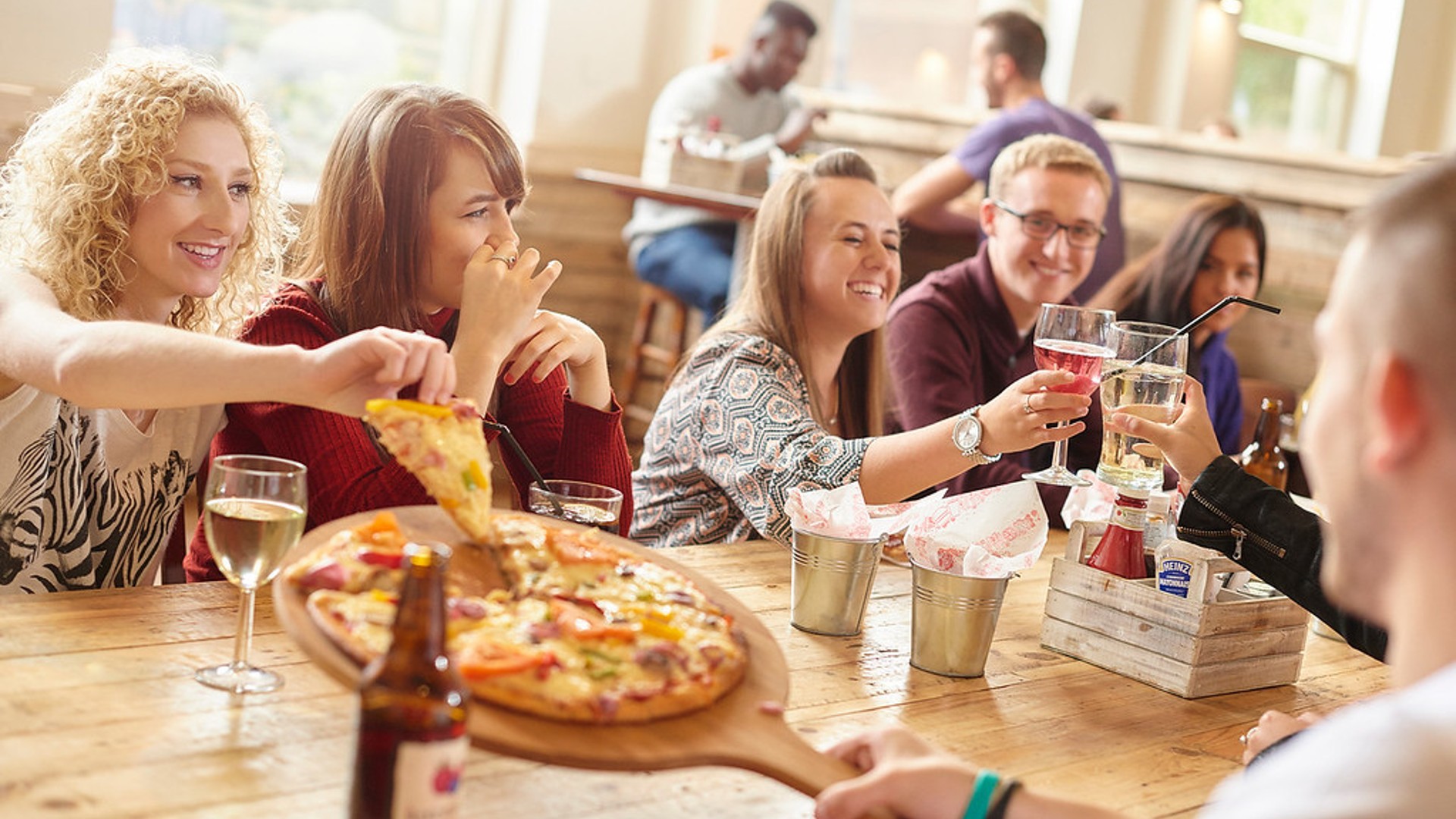 Students sharing a pizza and drinks in the SU Bar.