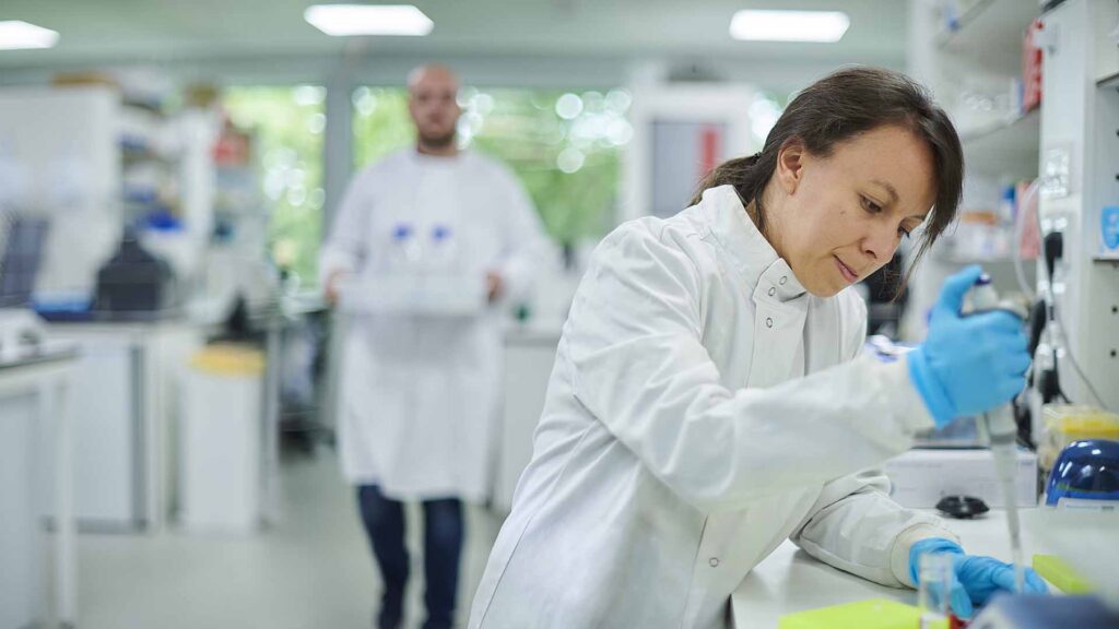 A student wearing a lab coat works with vials in one of our laboratory spaces.