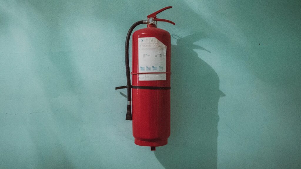 A fire extinguisher hanging up on a green wall