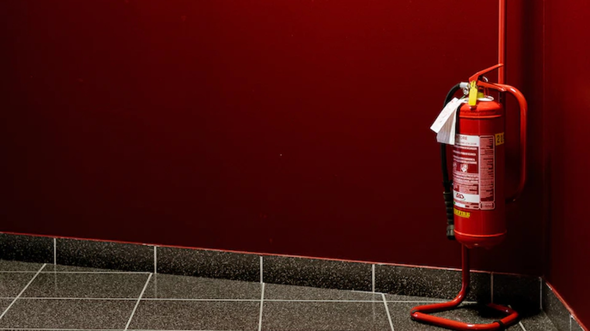 A fire extinguisher hanging up in a red hallway.