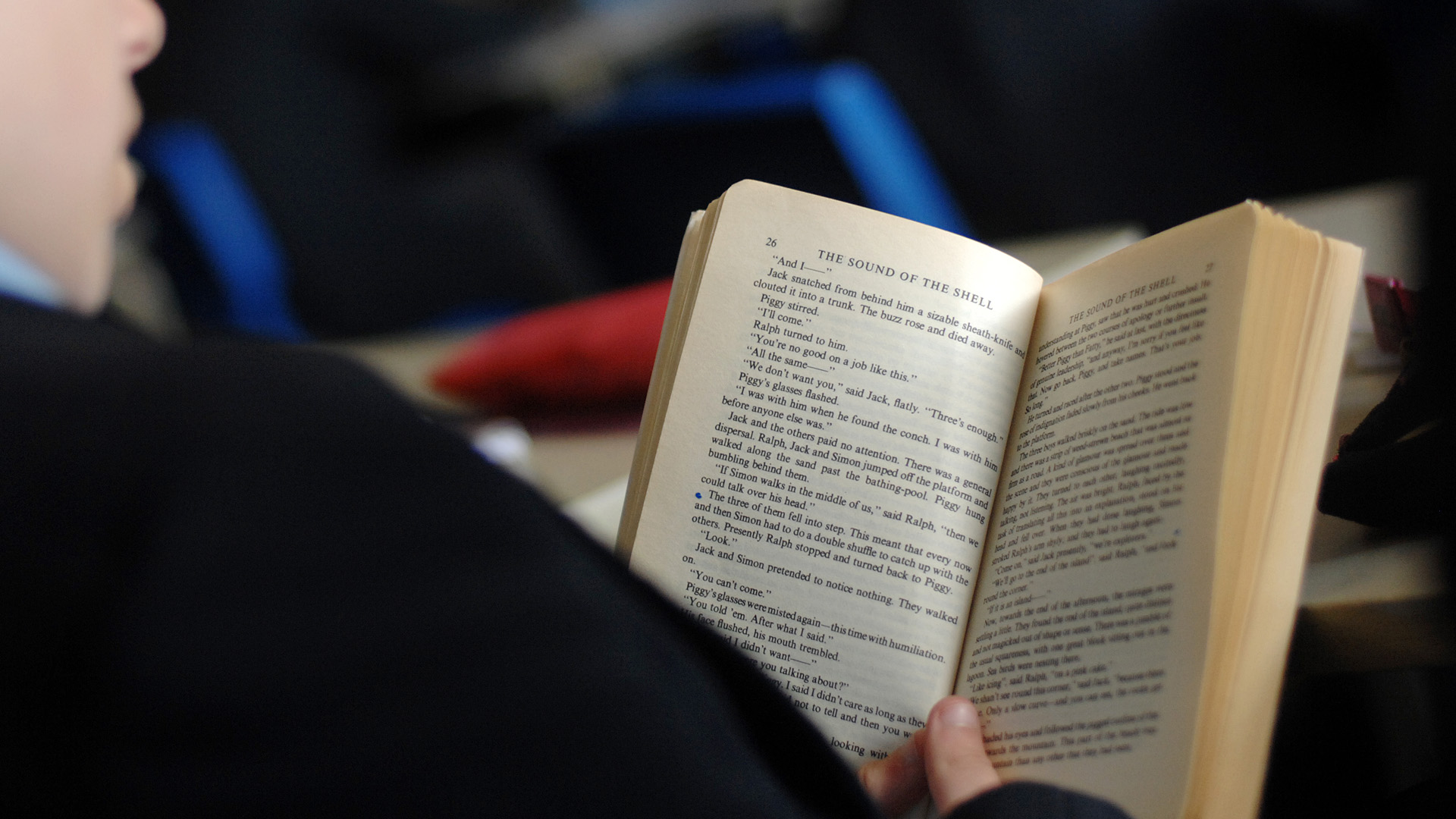 An open book being read by a person who is out of focus