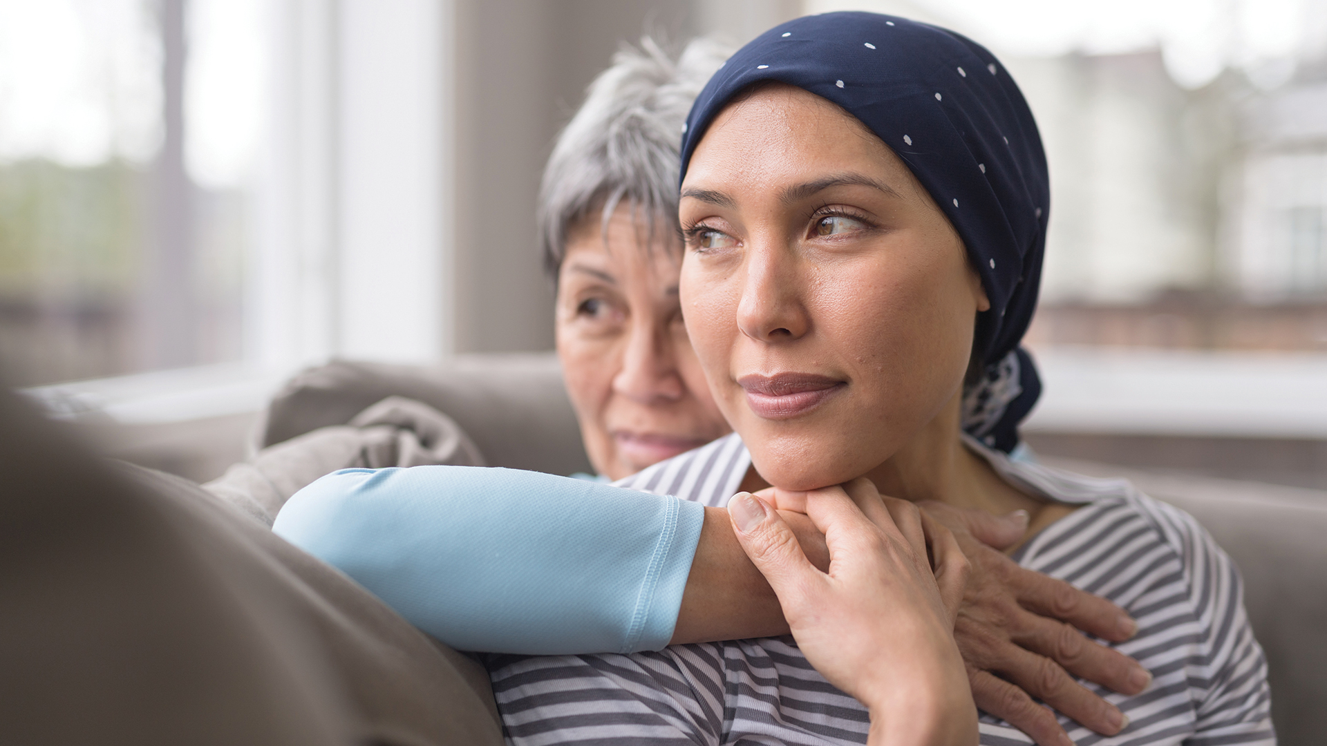 An Asian woman in her 60s embraces her mid-30s daughter who is battling cancer