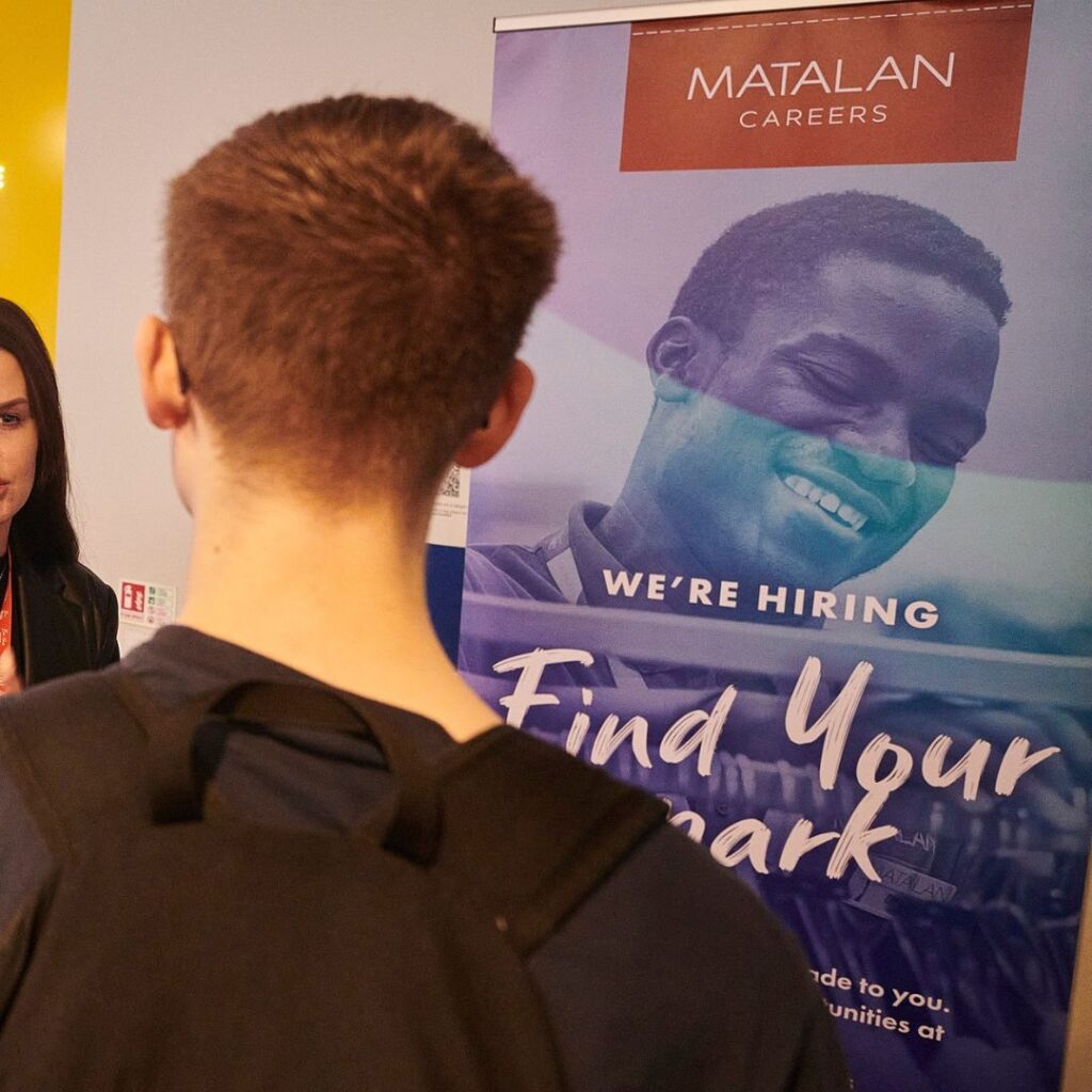 Student talking to Matalan at a careers fair. Back of students head and Matalan banner