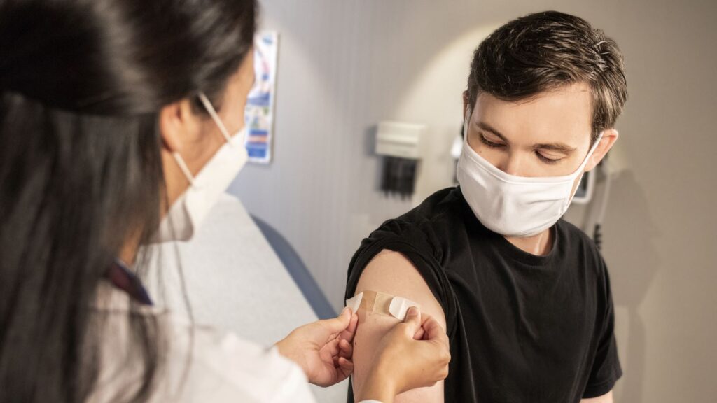 A picture of a health professional putting a plaster on a mans arm.