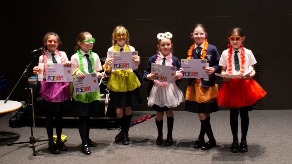6 children pose in fun neon accessories with their certificates for the Poetry Slam