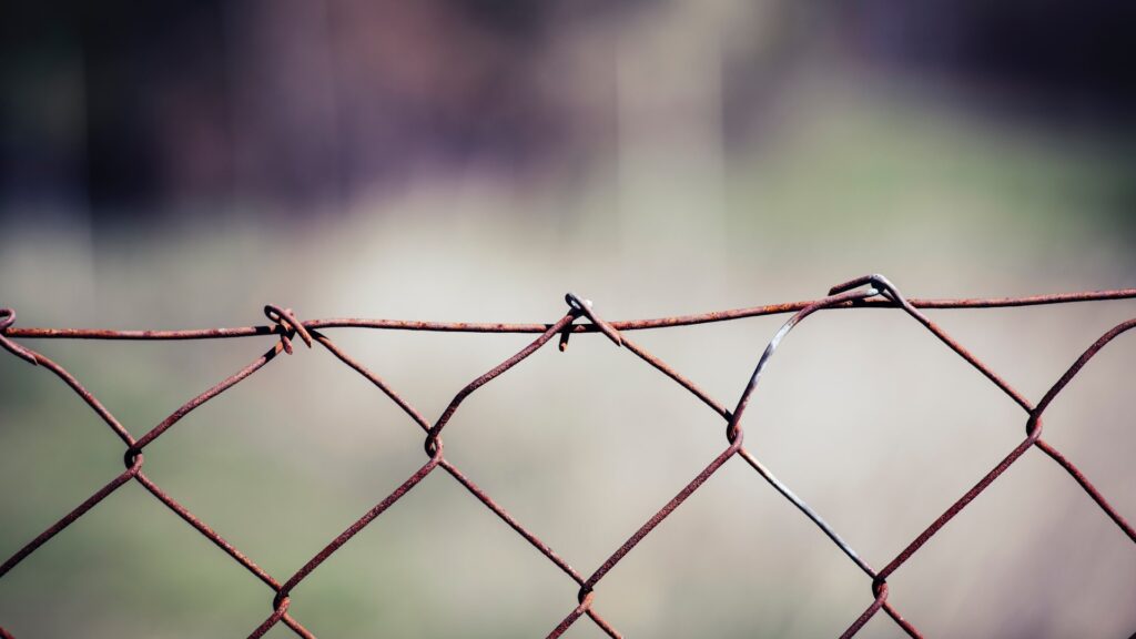 A picture of a wire fence with a blurred background. Edge Hill University is launching the International Justice and Human Rights Centre.