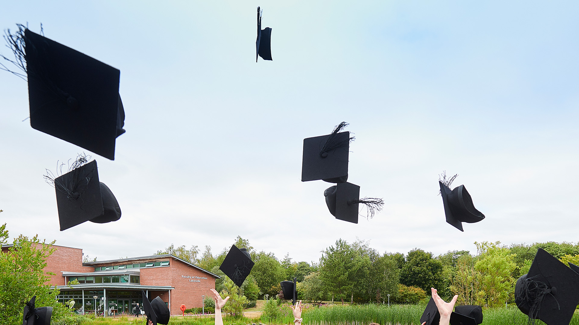 graduation hats being thrown in the air. summer blue sky