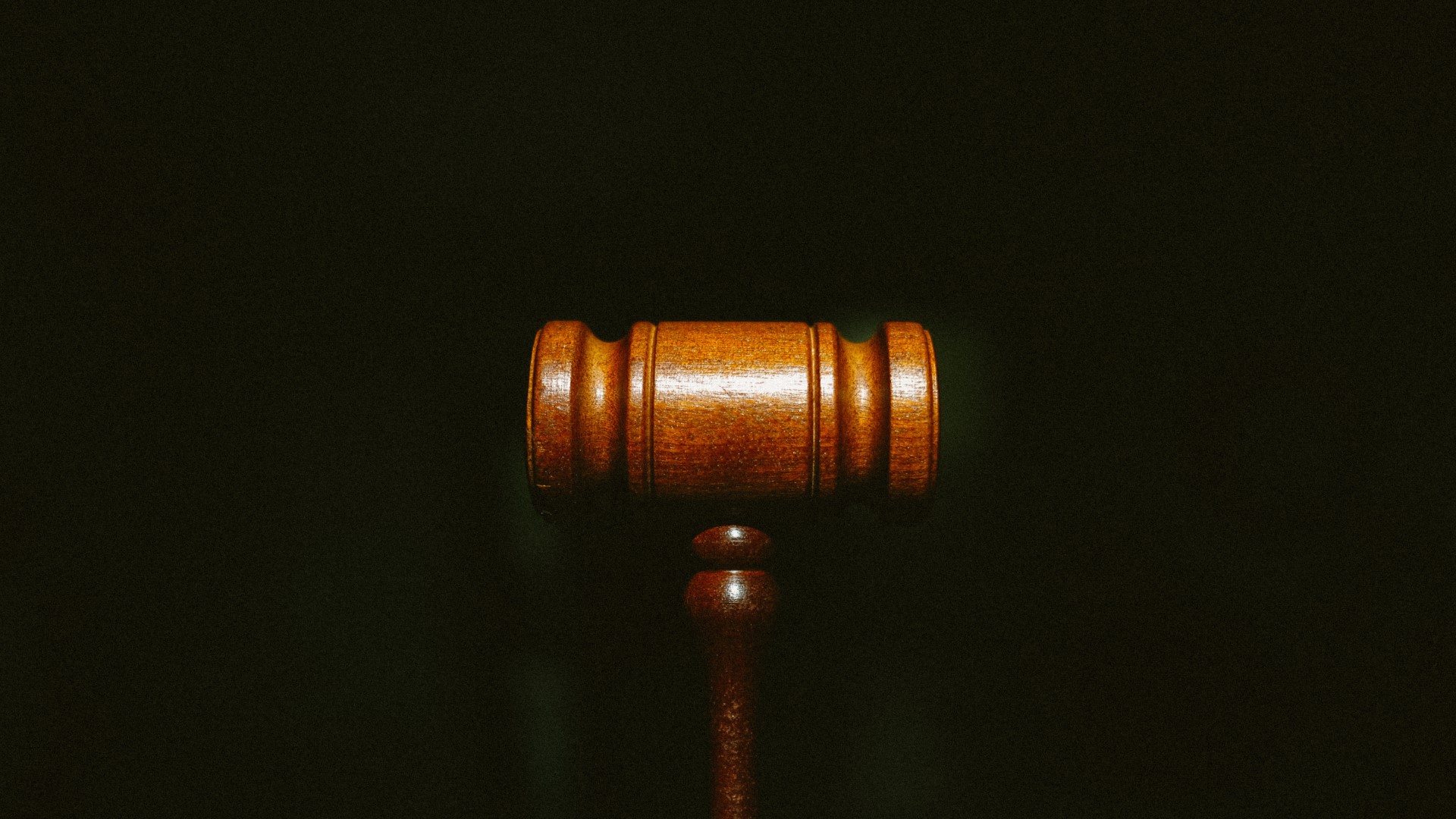 A brown wooden gavel against a black background.