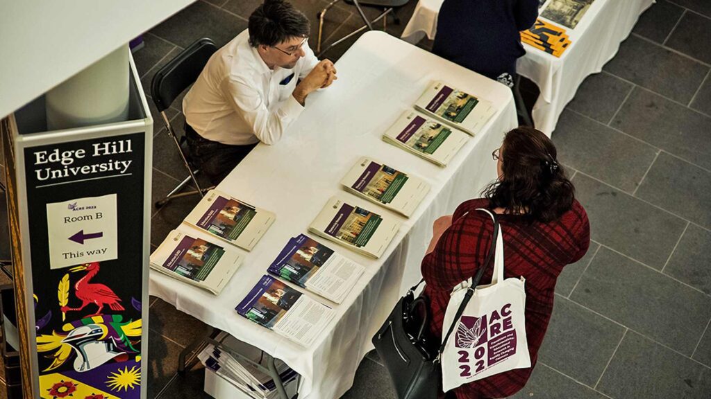 High angle shot of an attendee looking at programmes for the ACRE 2022 Transitions and Transformations event