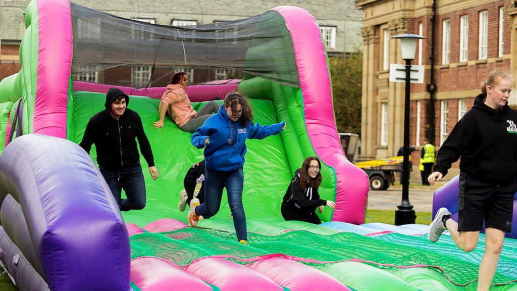 students playing on blow up slide outside main building