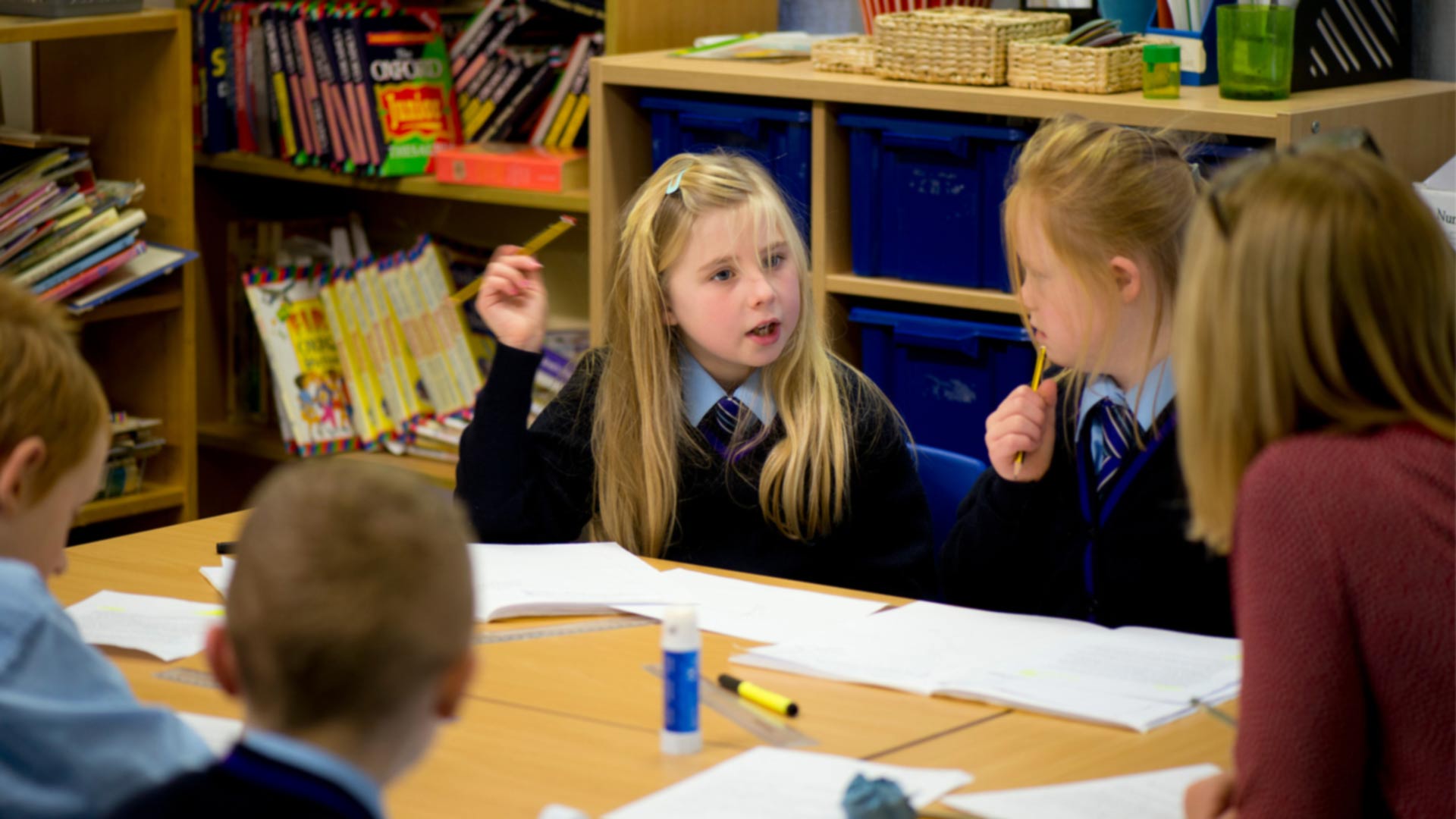 A teacher speaking to a group of primary school children in a classroom.