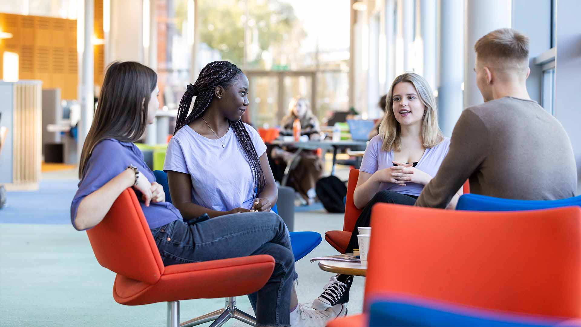 four students both male and female sat talking in the hub