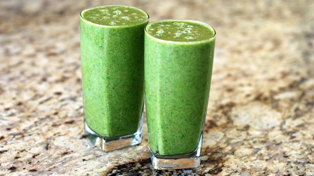 Two green breakfast smoothies on a kitchen counter