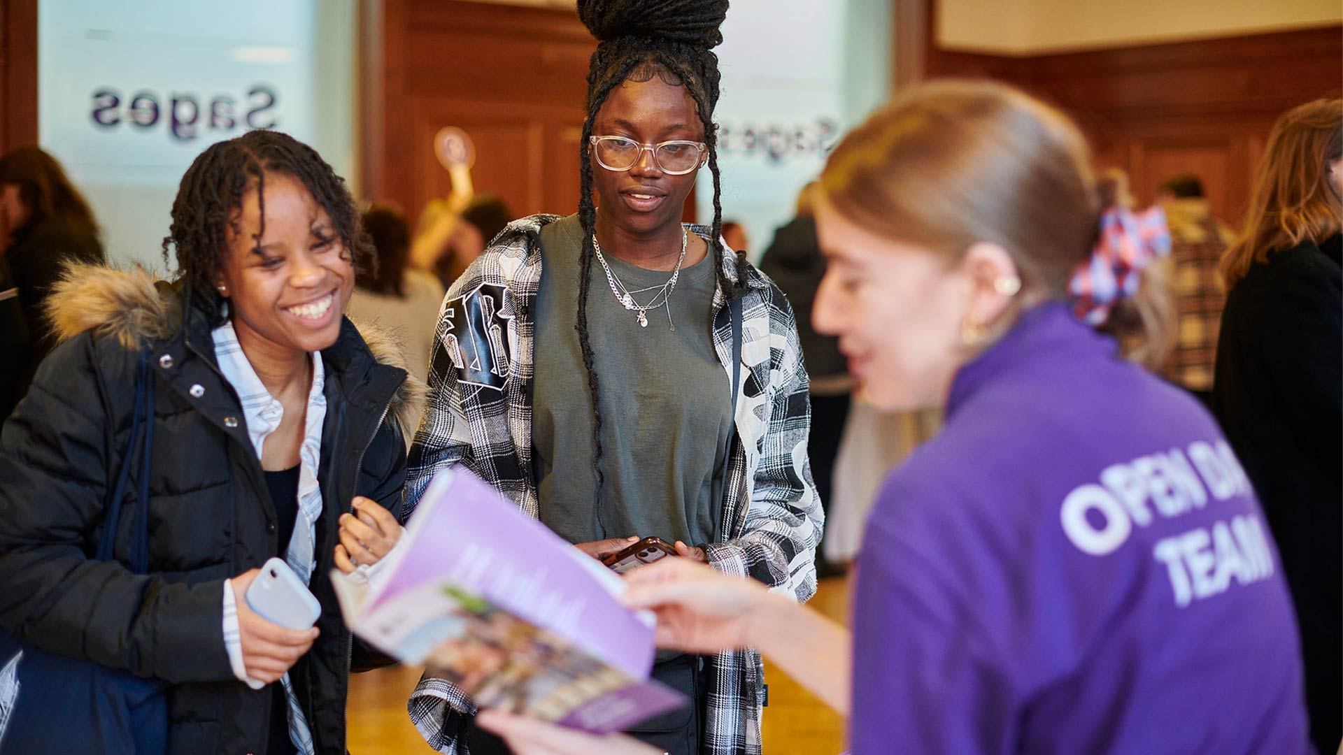 A member of staff helping prospective students at an open day.