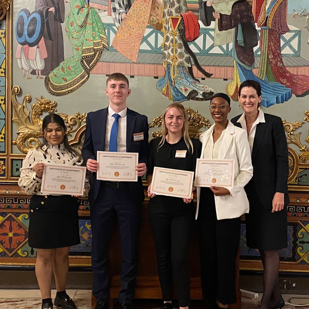 4 law students and lecturer holding certificates, facing camera at Madrid mooting competition