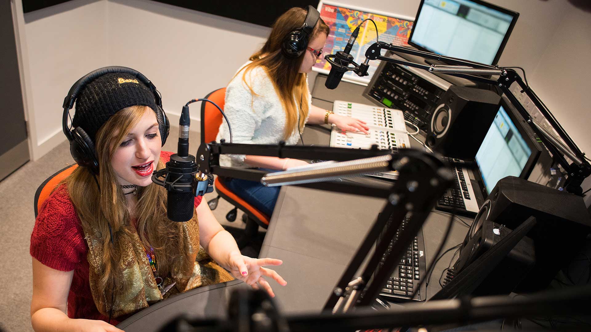 Female in a radio studio talking on a microphone.