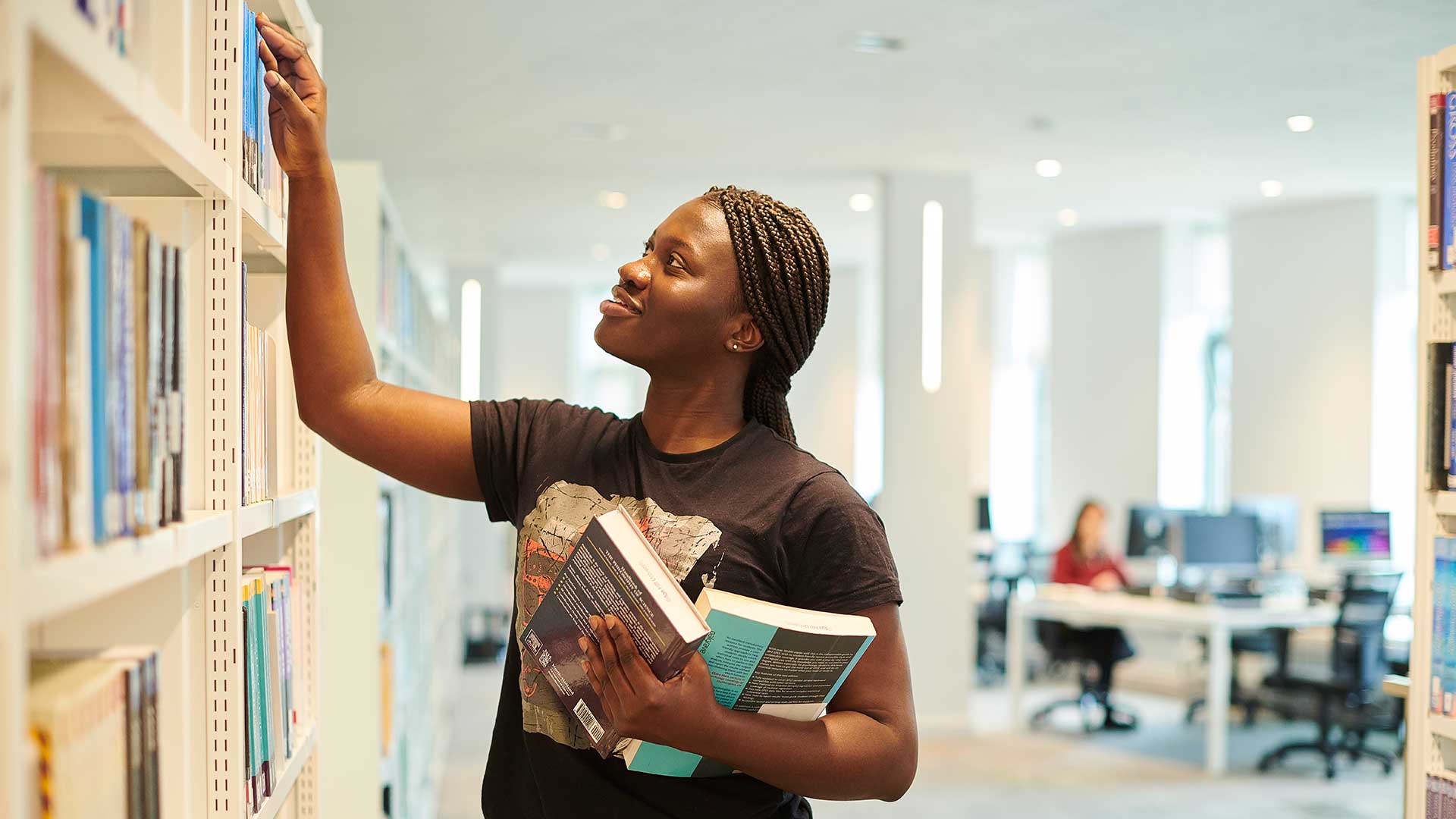 student in catalyst picking books from the shelves