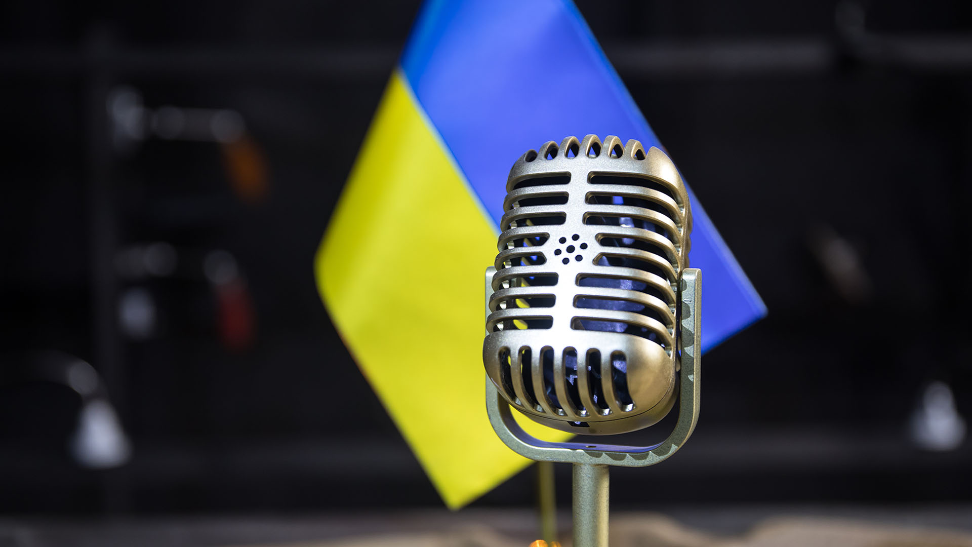 Microphone on a background of a blurry flag Ukraine close-up. dark table decoration. Selective focus