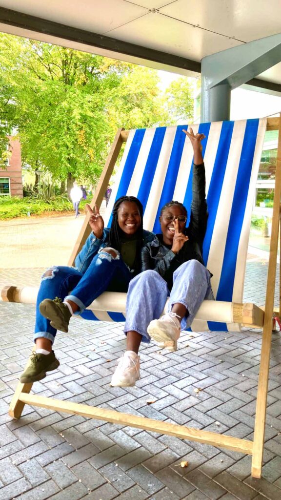 two female students on giant deckchair outdoors