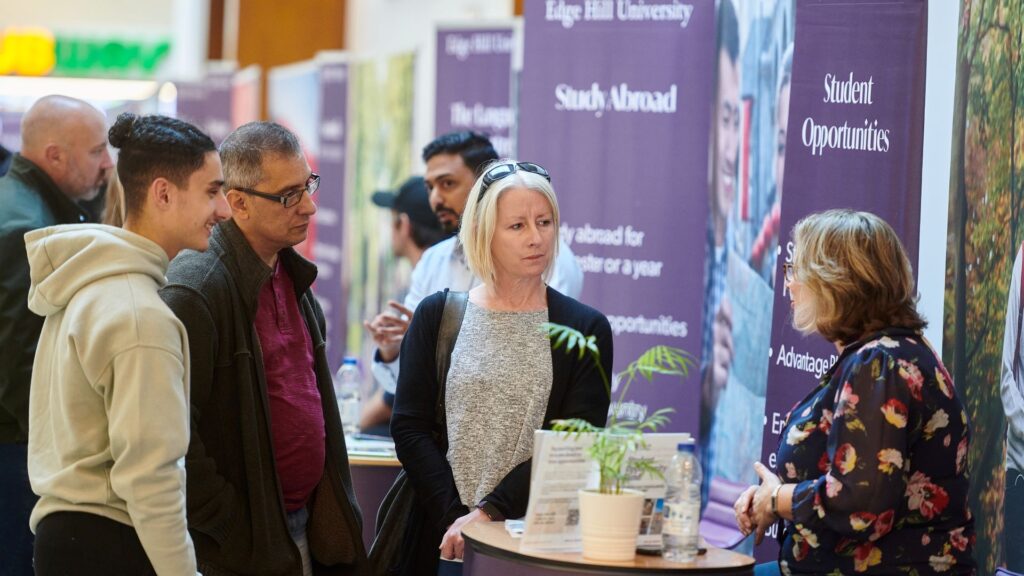 A prospective student and their parents gets advice from one of the student experience fair stalls at an Edge Hill University open day.