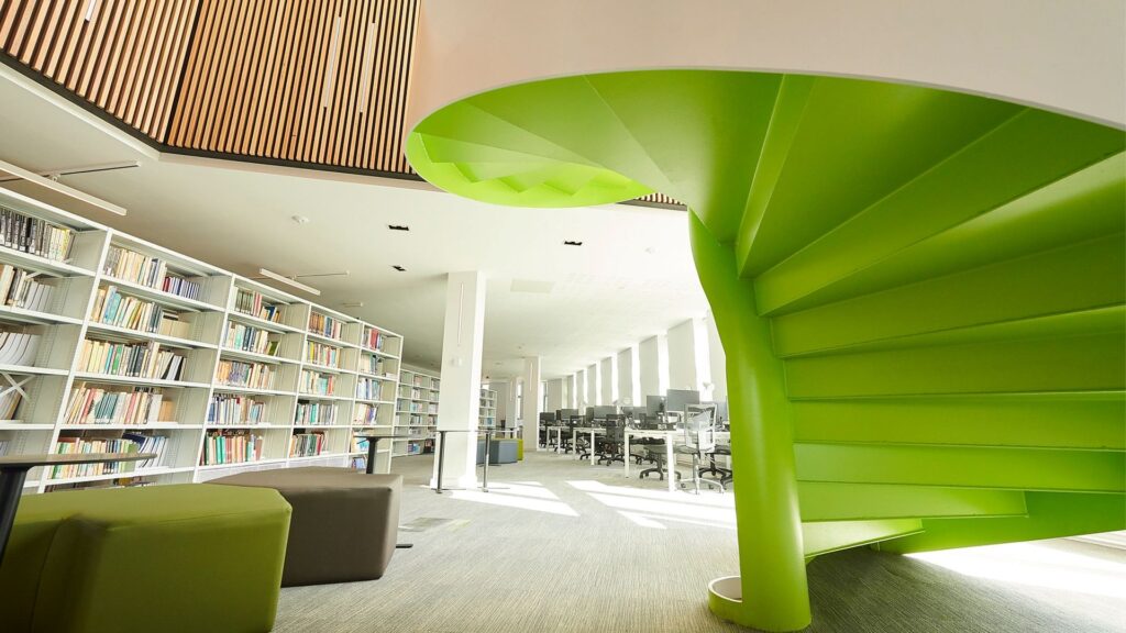 A shot of the spiral staircase, bookshelves and seating on the second floor of Catalyst.