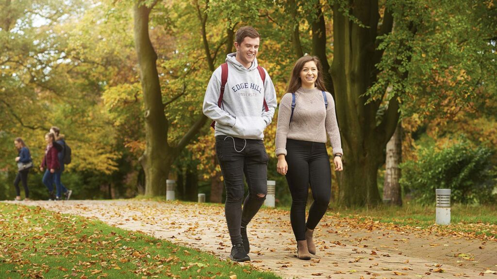 Two students walking through a leafy path on campus