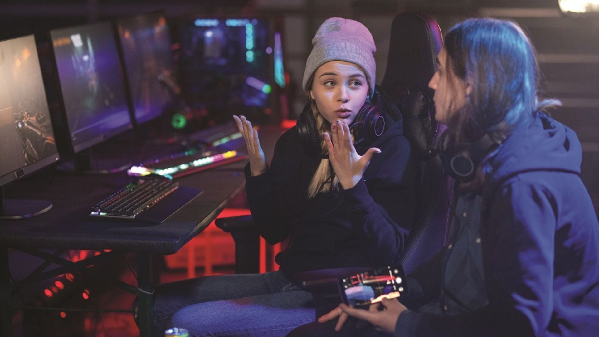 two students talking sat at a computer