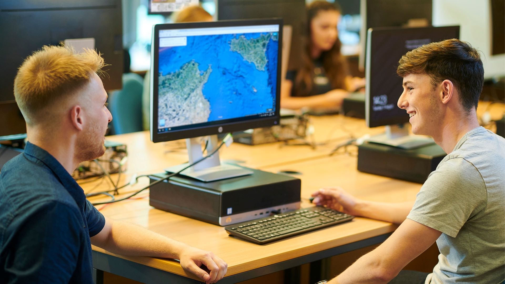 Two students look at a map on a computer.