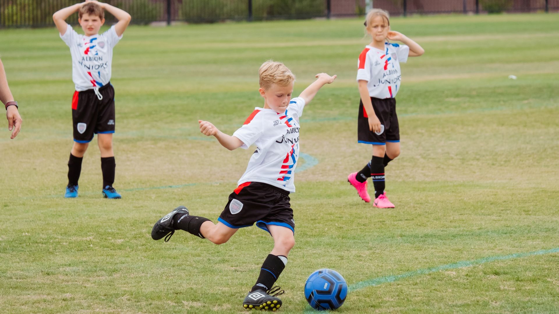 Photo of a young boy kicking a football in a game.