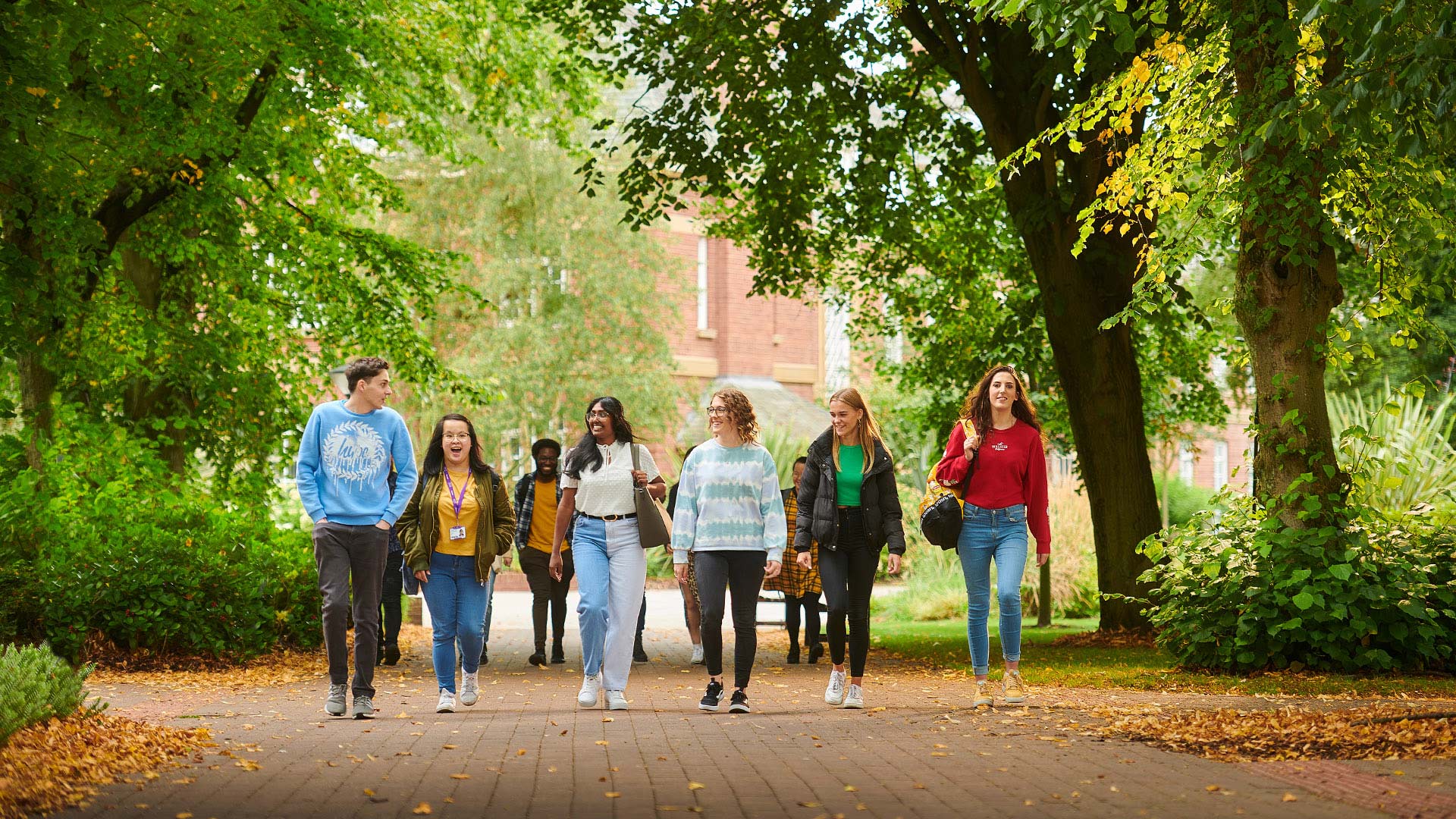 A group of students walking in a leafy area on campus