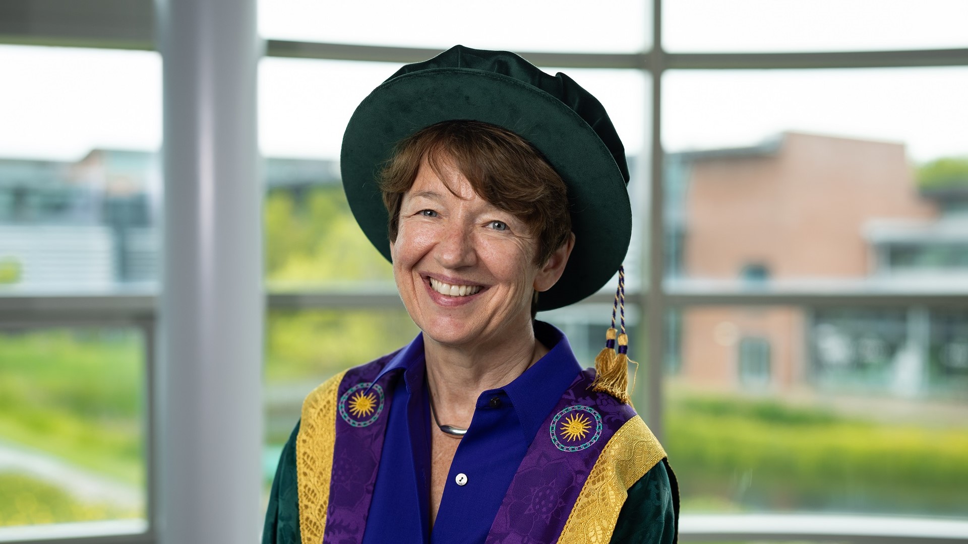 Dawn Airey wears a dark green hat with golden tassle and purple, gold and green robes.