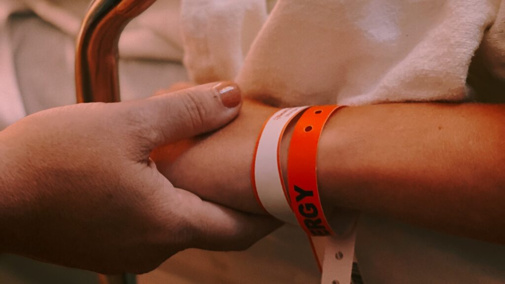 A close up of an adult holding a child's hand as they lie in a hospital bed.