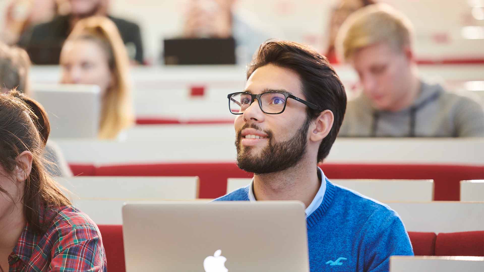 A student in a blue jumper in a lecture theatre.